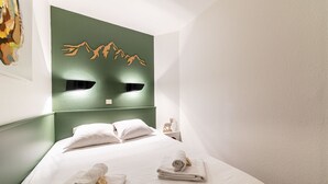 A hotel room with a green accent wall, a bed with white linens, and a small decorative deer figure on the nightstand. - Immodreams - La Fruitière - Avoriaz (Avoriaz)