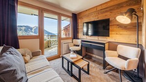 A cozy living room with a sofa, chairs, a coffee table, and a fireplace. Large windows offer a mountain view. - Immodreams - La Fruitière - Avoriaz (Avoriaz)