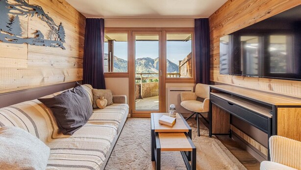 A cozy room with a sofa, a small table, a TV, and a view of mountains through large windows. - Immodreams - La Fruitière - Avoriaz (Avoriaz)
