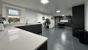 Una cocina moderna con una isla grande, muebles oscuros y vistas al exterior.