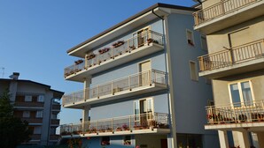 A multi-story residential building with balconies, each adorned with potted plants. - Charming Flat Close to the Beach (Caorle)