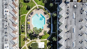An aerial view of a hotel with a central swimming pool, surrounded by lounge areas and greenery. - Paradise Found! Stop Looking! (Galveston)