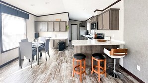 A modern kitchen with grey cabinets, a central island, and two bar stools. - Adventure Await! 20minute to Abraham Lake Ice Bubbles, Full home+ Mountain views (Nordegg)