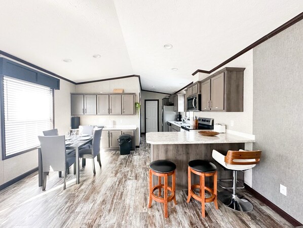 A modern kitchen with grey cabinets, a central island, and two bar stools.