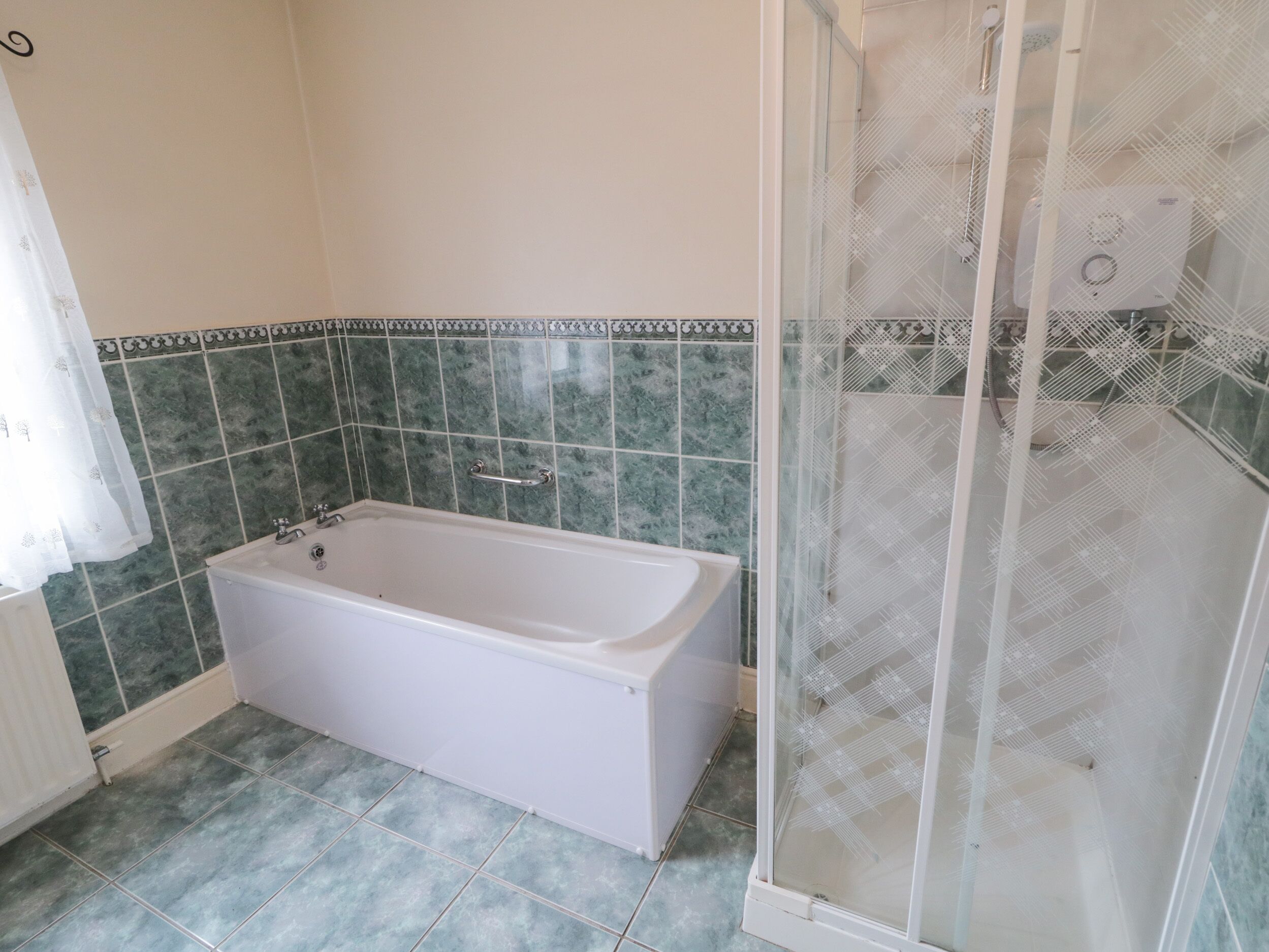 Un baño con bañera, cabina de ducha y azulejos de mármol verde.