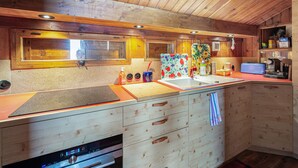 A kitchen with wooden cabinets, a sink, a microwave, and a window with blinds.