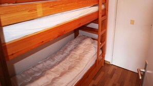 A bunk bed with a wooden frame and a white mattress.
