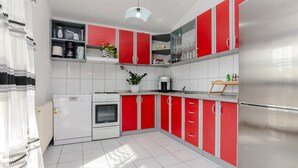 A modern kitchen with red and white cabinetry, a built-in oven, a refrigerator, and a coffee machine. - 3 bedroom awesome apartment in Vir (Vir)