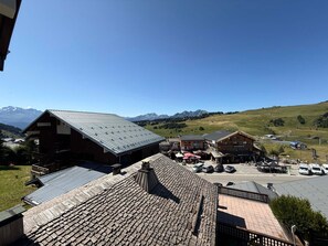 Un pueblo de montaña con edificios de madera tradicionales, un área de estacionamiento y una vista despejada de las montañas circundantes.