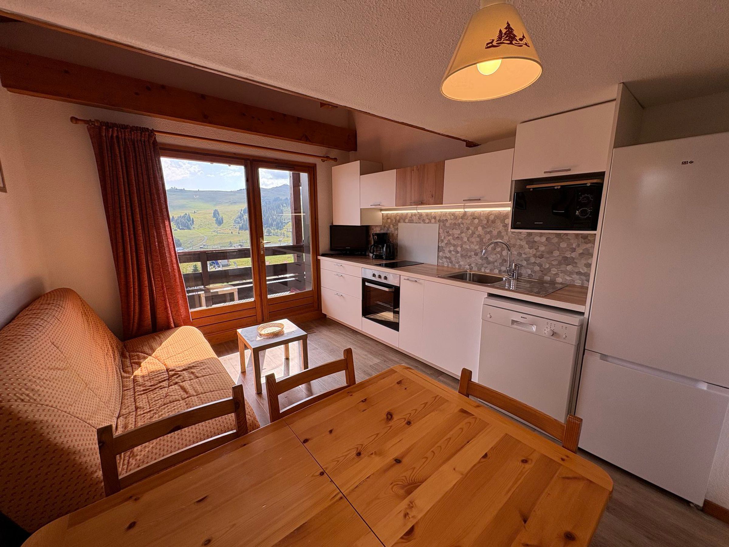 Una cocina compacta con comedor, un sofá y vistas a través de un ventanal grande.