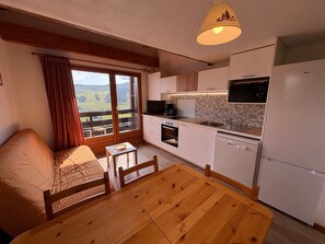 Una cocina compacta con comedor, un sofá y vistas a través de un ventanal grande.