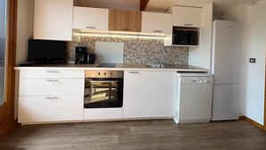 Una cocina moderna con armarios blancos, horno empotrado, microondas y lavavajillas.