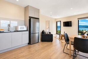 A modern kitchen with a built-in refrigerator, a dining area with a table and chairs, and a seating area with a sofa.