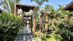 A pathway with a geometric tile pattern leading to a covered area with hanging lamps. - Just B Boutique Hotel (Vagator)