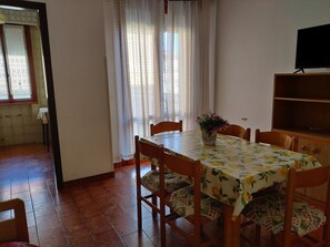 Un área de comedor con una mesa cubierta por un mantel floral, rodeada de sillas de madera.