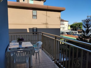 A balcony with a table and chairs, a potted plant, and a view of the cityscape.