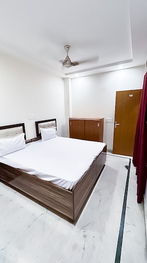 A bedroom with a bed, wardrobe, and ceiling fan. - Roomshala 138 Hotel Tourist palace (New Delhi)