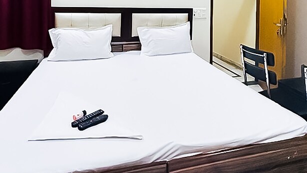Habitación de hotel con cama, ventilador de techo, aire acondicionado, armario y espejo.