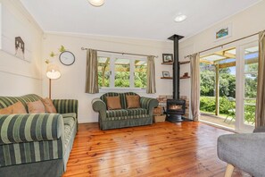A cozy living room with a fireplace, two sofas, and a large window with curtains.