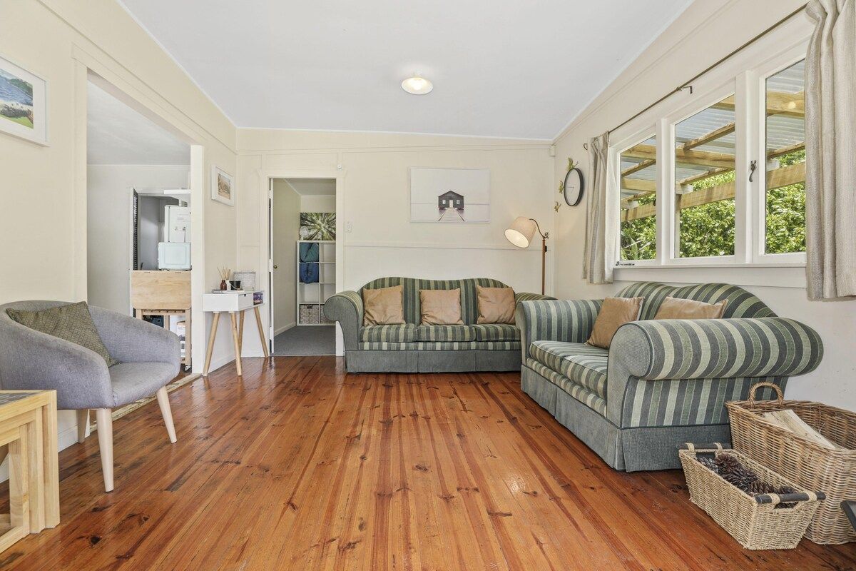 A cozy living room with a wooden floor, two sofas, a chair, and a desk.