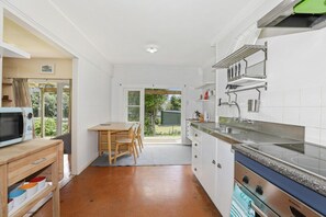 A kitchen with a microwave, stove, and a dining area with a table and chairs.