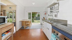 Une cuisine compacte avec des meubles blancs, un four à micro-ondes, une cuisinière et un coin repas comprenant une table et des chaises.