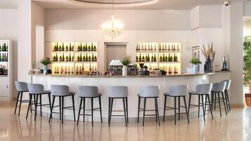 Zona de bar con mostrador central, varias estanterías llenas de botellas y taburetes.