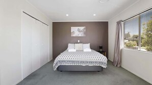 Ein Schlafzimmer mit Bett, Kleiderschrank, Nachttisch und einem fenster mit Vorhängen.