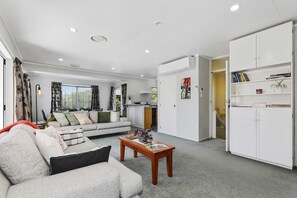 A modern living room with a sofa, coffee table, and a bookshelf. - Stay at 5A - Spa Pool, Steps to the Redwoods (Rotorua)