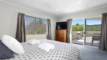 Un dormitorio con cama, cómoda, televisor y balcón con vistas.