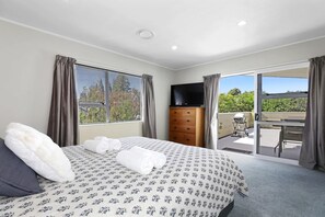 Une chambre à coucher avec un lit, une commode, une télévision et un balcon offrant une vue.