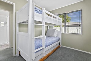 A bunk bed with a window view, carpeted floor, and a door. - Stay at 5A - Spa Pool, Steps to the Redwoods (Rotorua)