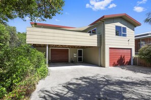 A two-story house with a garage, a covered driveway, and a red roof.