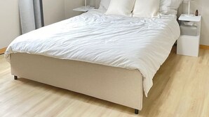 Une chambre à coucher au style minimaliste, avec un lit, deux tables de chevet et une fenêtre avec des rideaux.