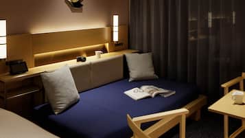 Habitación de hotel con cama, mesitas de noche, lámpara, una obra de arte en la pared y ventana con cortinas.