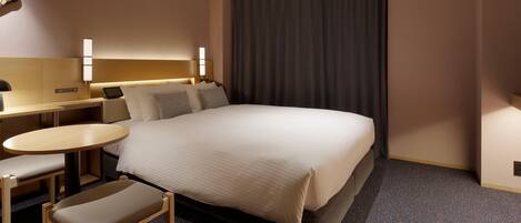 A hotel room with a large bed, a desk with a chair, a small table, and a large window with curtains.