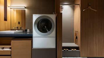 Un moderno lavadero con lavadora de carga frontal, armarios de madera, un lavabo y un zapatero.