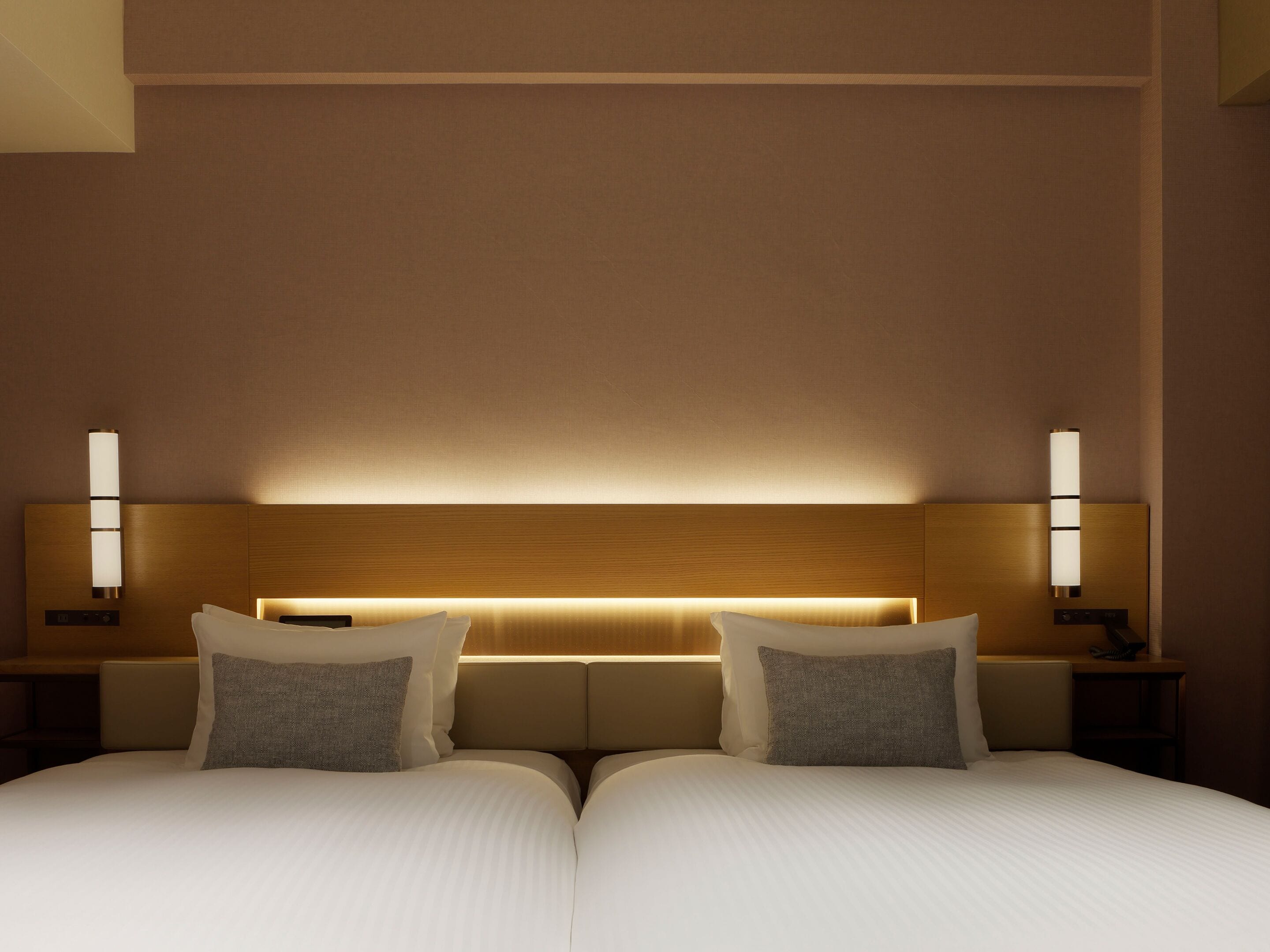 A double bed with a wooden headboard, two bedside tables with lamps, and a neutral wall color.