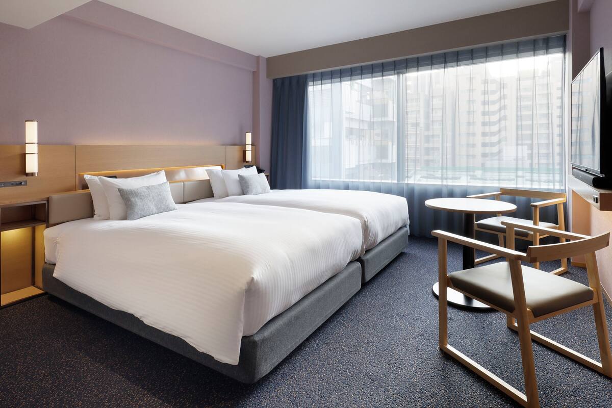 Ett hotellrum med en stor säng, ett skrivbord och en stol.