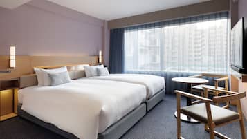 A hotel room with a large bed, a desk, and a chair.