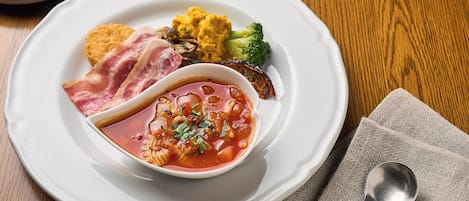 A plate of food with a bowl of soup, broccoli, and bread.