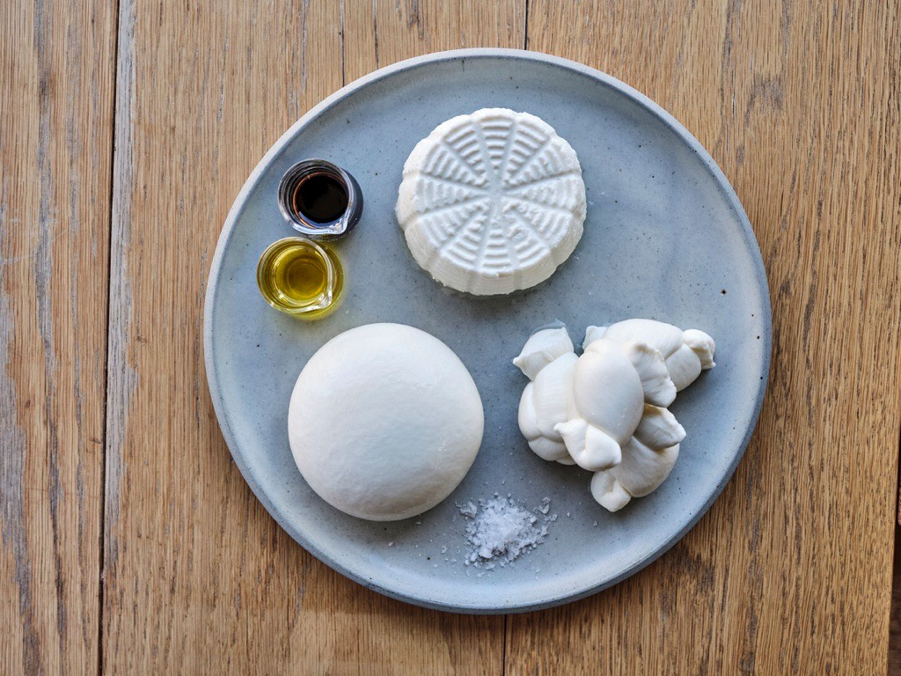 A plate with various food items and condiments on a wooden table.