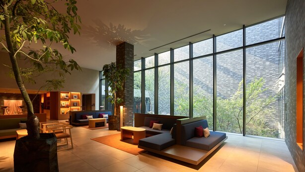 A spacious living area with large windows, a modern sofa set, a coffee table, and a bookshelf. - Mitsui Garden Hotel Kyoto Sanjo PREMIER (Kyoto)