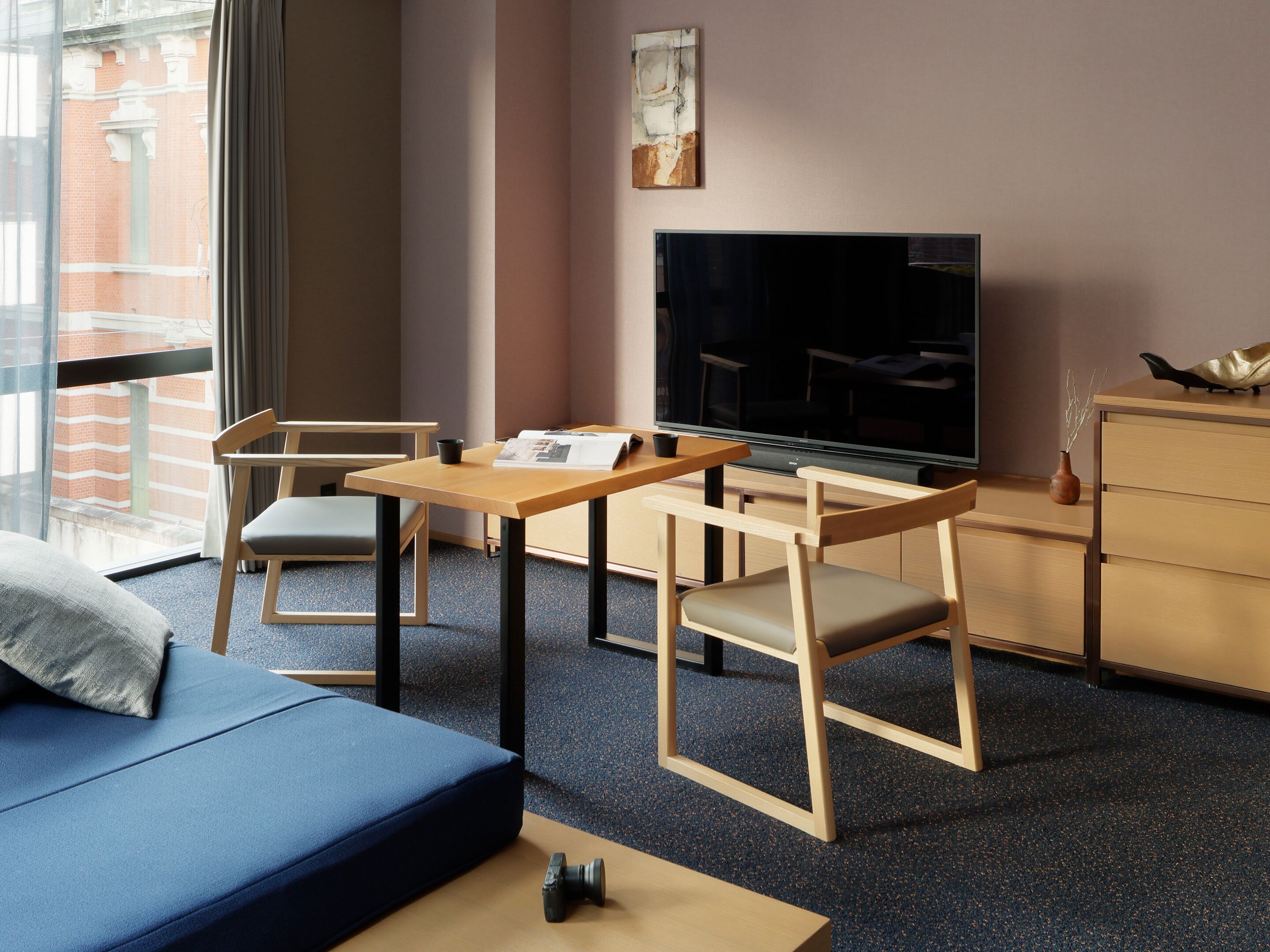 Ein modernes Zimmer mit einer Couch, einem Fernseher, einem Holztisch und einem Stuhl.
