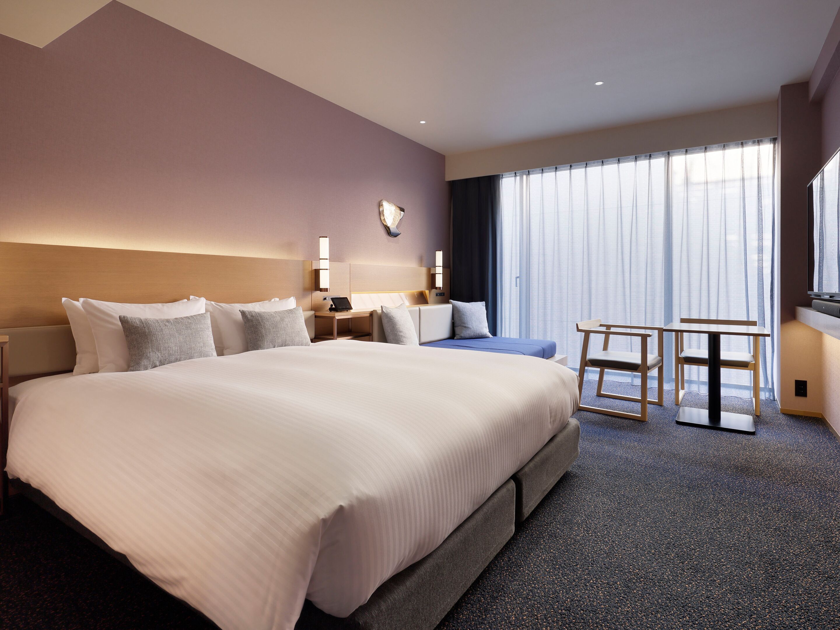A hotel room with a large bed, bedside tables, a desk, and a chair.