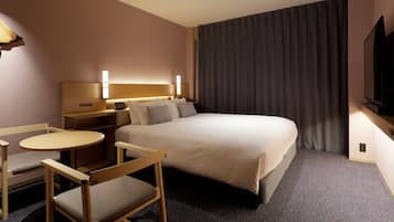 Une chambre d’hôtel avec un lit, des tables de chevet, un bureau, une chaise, une télévision et un rideau.