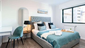 Un dormitorio moderno con cama, escritorio, silla y ventana.