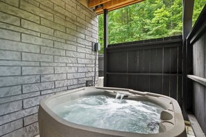 Ein Whirlpool mit Holzterrasse und Backsteinwand im Hintergrund.