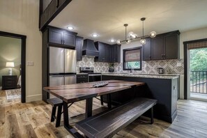 Une cuisine moderne avec des meubles de couleur sombre, un grand îlot central et un banc en bois.