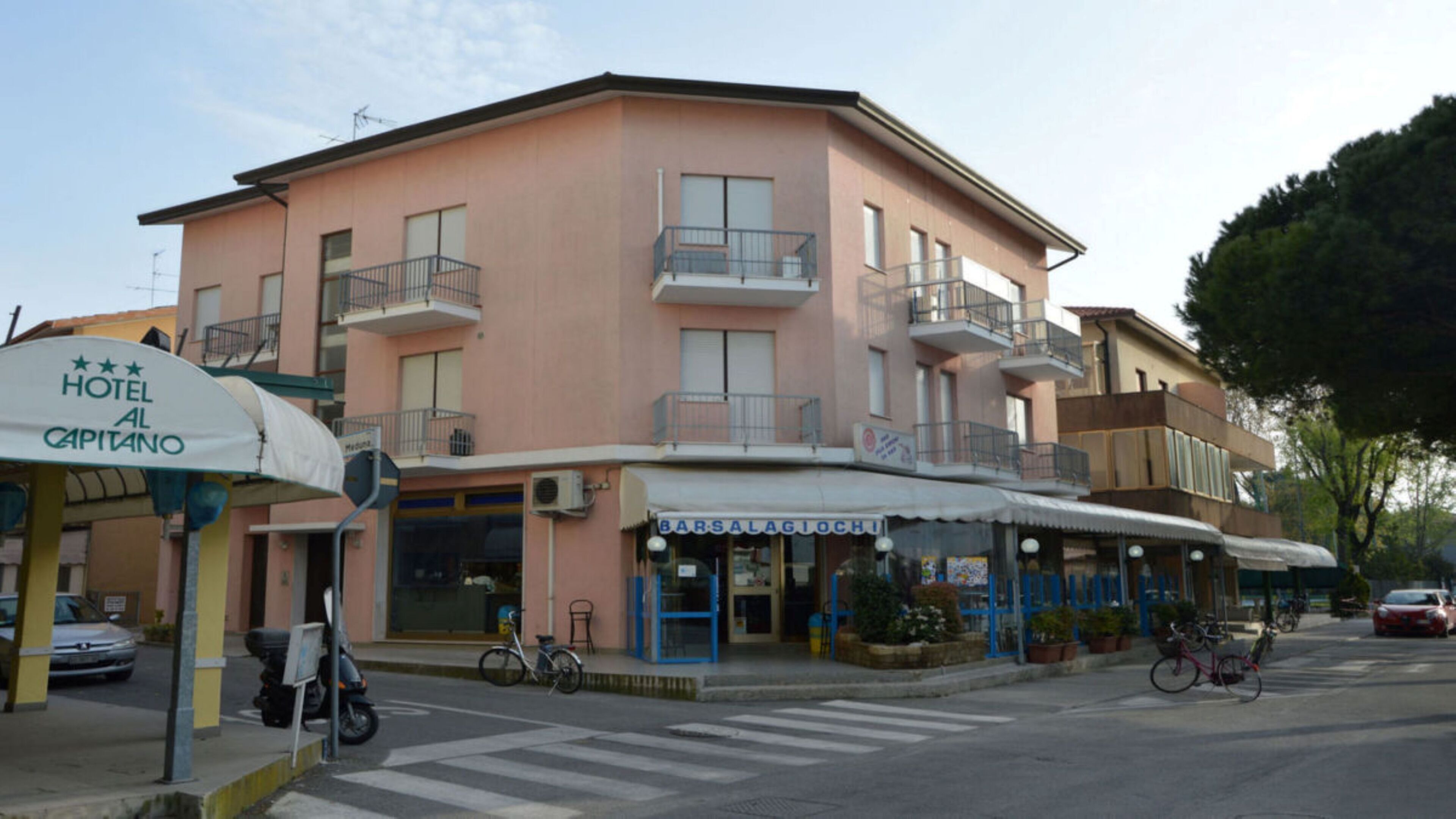 A hotel with a pink facade, multiple balconies, and a storefront named 'Barsalagioch.'